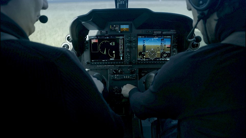 Schulterblick auf zwei Hubschrauberpiloten im Cockpit