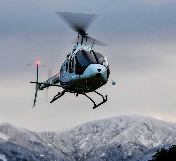 Hubschrauber vor schneebedeckten Bergen