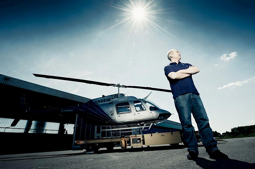 Mann steht draußen vor einem Hubschrauber und Hangar