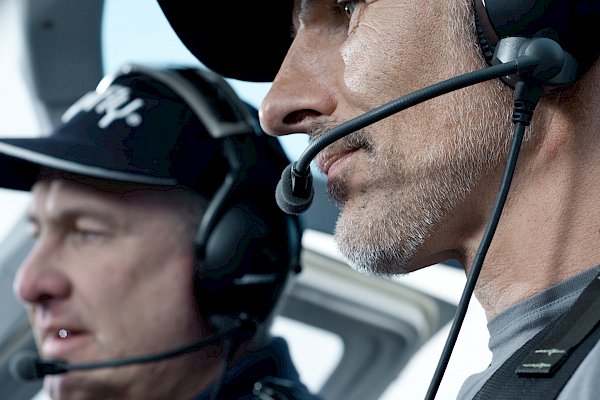 Zwei Männer mit Kopfhörern im Hubschrauber-Cockpit